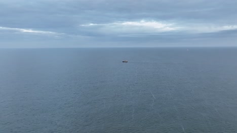 Fly-over-drone-shot-of-a-Fishers-boat-dragging-the-nets-thru-the-water-of-the-shore-of-Ameland