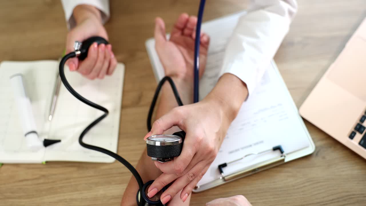 Doctor measures blood pressure to the patient using mechanical sphygmomanometer in clinic closeup