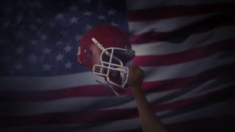 american football player holds his helmet up in air