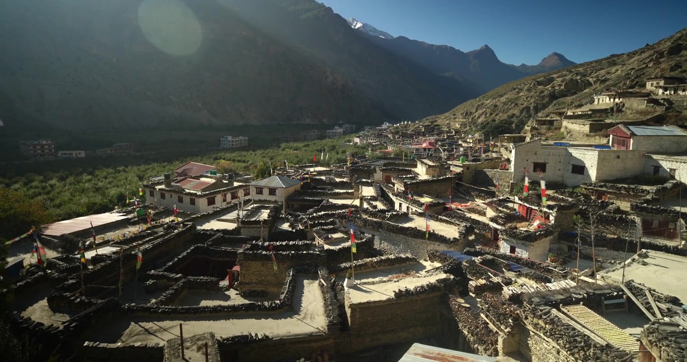 Villaggio di Marpha, Mustang, Nepal, scatto panoramico che si affaccia su tradizionali case in pietra imbiancate a calce con tetti piatti, bandiere di preghiera svolazzanti e un drammatico paesaggio di valle montano