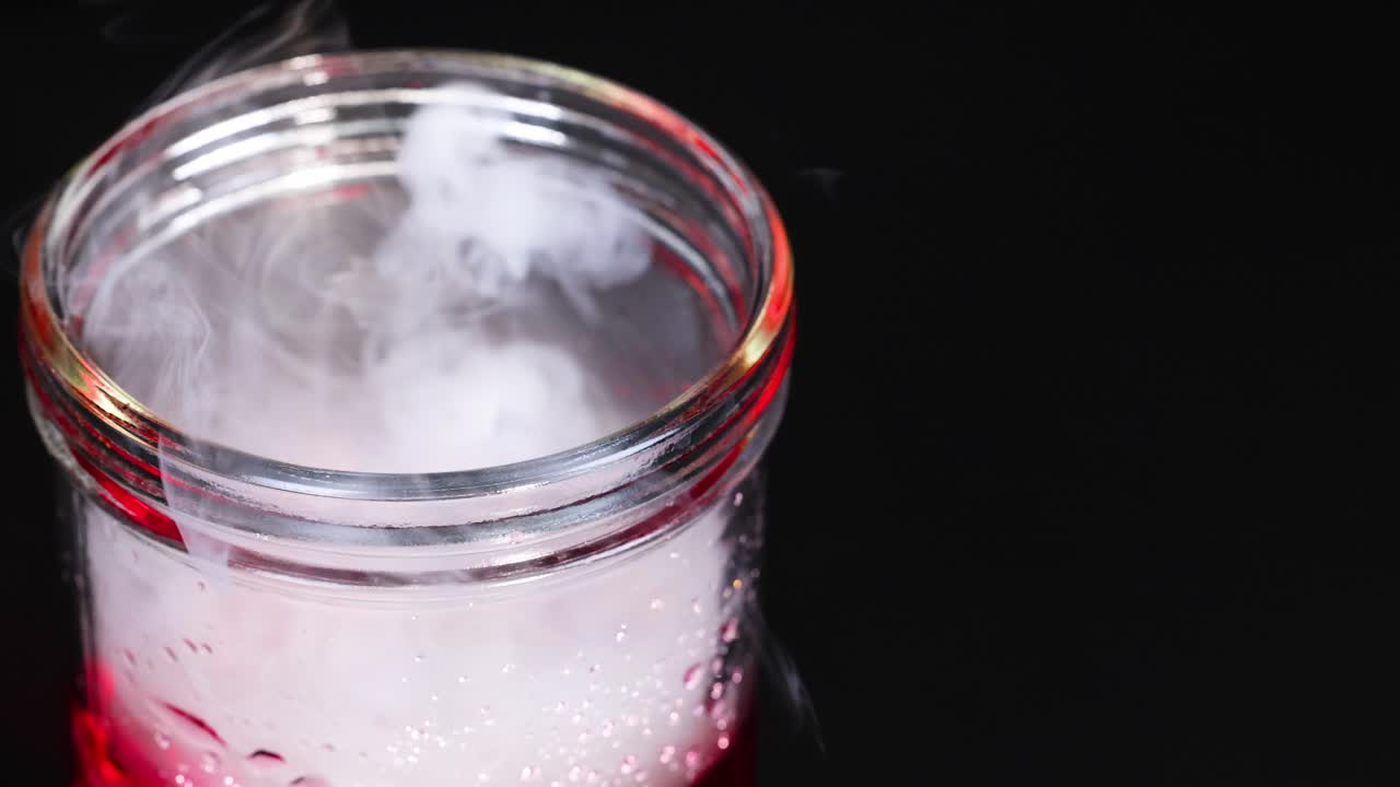 A beaker with dry ice creates swirling vapor, showcasing a chemical reaction in a controlled environment with dramatic lighting