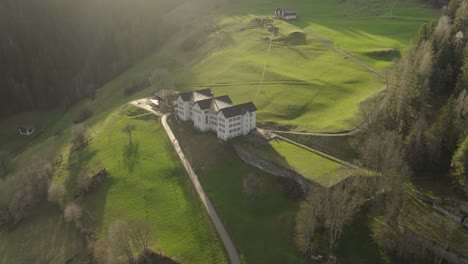 Aerial-of-an-old-building-in-a-swiss-mountain-valley-in-summer-at-sunset