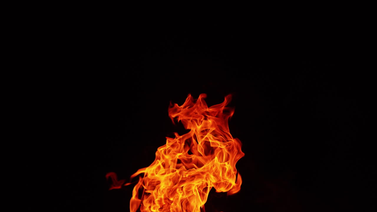 Tongues of campfire flames striving up into the air. Top part of the bonfire isolated at black backdrop.