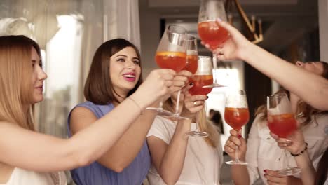 Hen-party-of-adult-women-indoors.-Close-up-of-the-girls-got-together-for-a-bachelorette-party.-They-drink-cocktails-from-big-wine-glasses.-Laughing.-Happy-and-positive