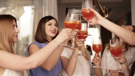 hen party of adult women indoors. close up of the girls got together for a bachelorette party. they drink cocktails from big wine glasses. laughing. happy and positive