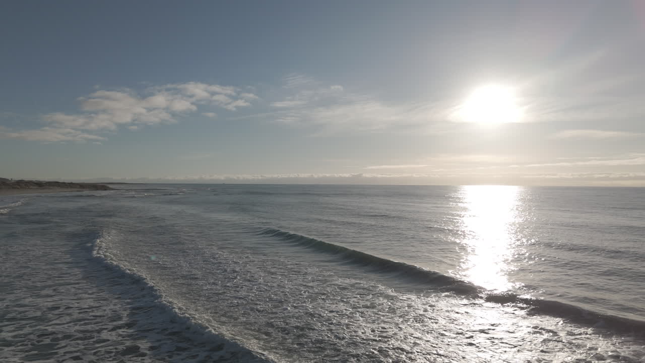 Backwards flying drone shot over waves near Borestranda Norway during sunset going away from the water LOG