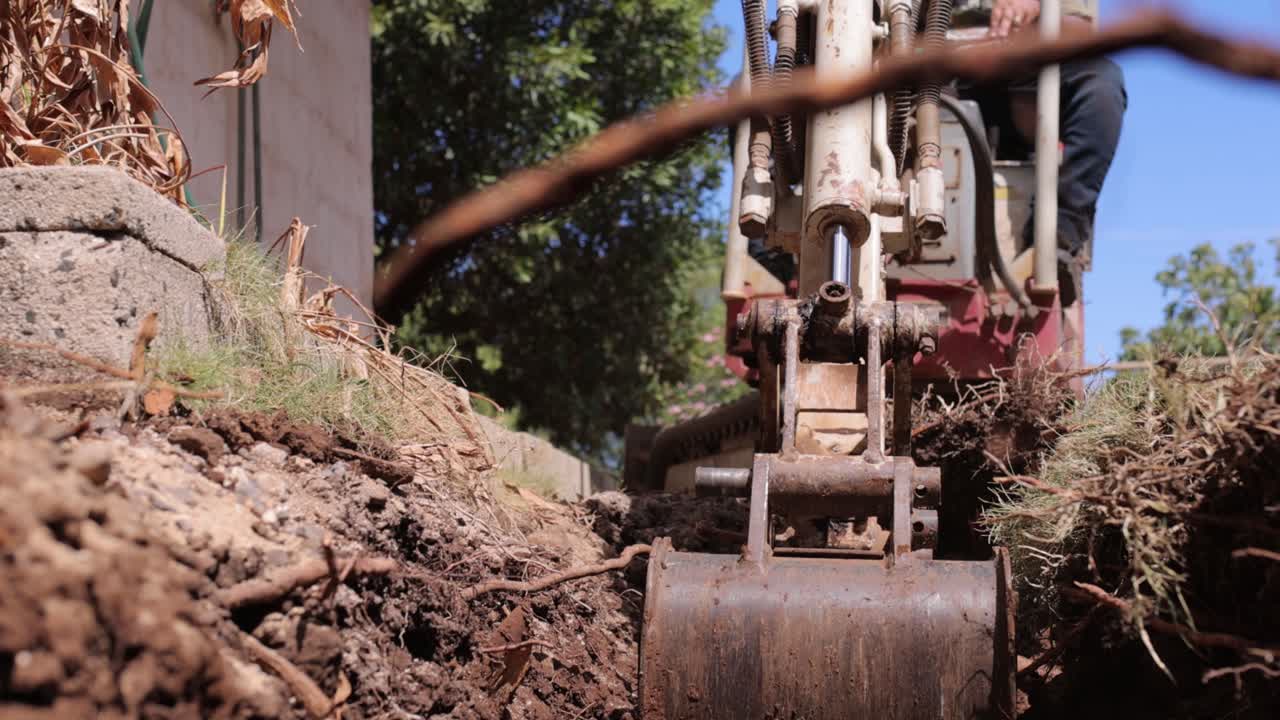 Hand-held Footage Of A Man Using An Excavator To Remove Dirt Out Of The Hole