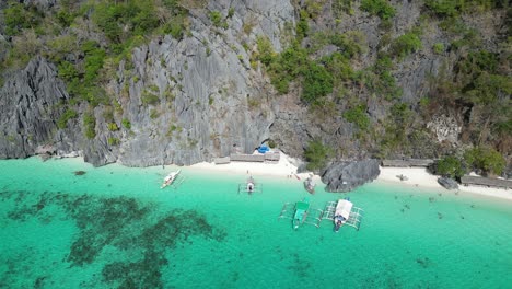 aerial view of tropical beach with boats and limestone cliffs