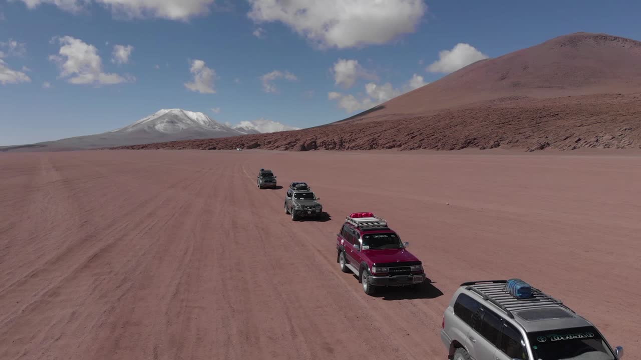 SUVs Traversing a Vast Red Desert Landscape with Mountains