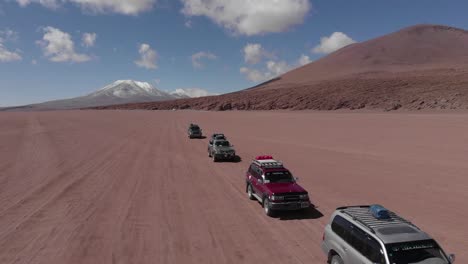 suvs traversing a vast red desert landscape with mountains