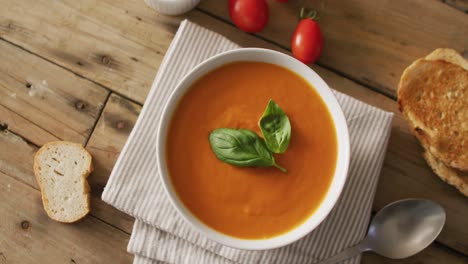 video of cream tomato soup in bowl on wooden table with bread