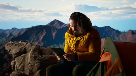 male hiker struggles to work online in windy conditions on remote mountain peak