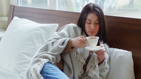 Young-woman-wrapped-in-blanket-having-tea-4k