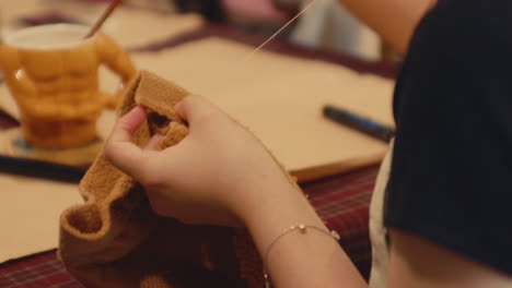 person sewing brown fabric