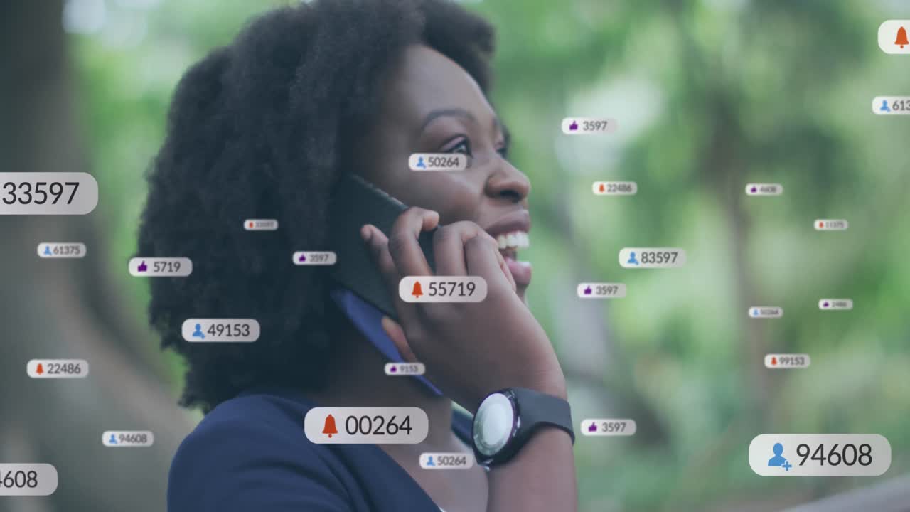 Animasjon av ikoner fra sosiale medier over en afroamerikansk kvinne som snakker i smarttelefon utendørs.