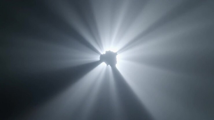 Raggi di luce intensa che brillano attraverso un piccolo foro su sfondo scuro