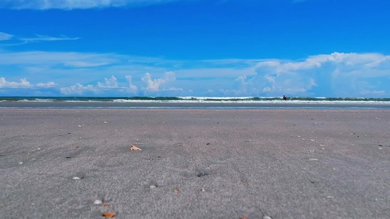 Serene Beach Day: Blue Sky, Calm Waves, and Sandy Shores