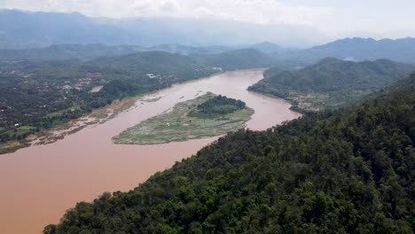 aerial flying over tropical forest hill with view of mekong river