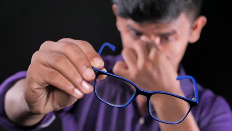 young man holding glasses with eyestrain