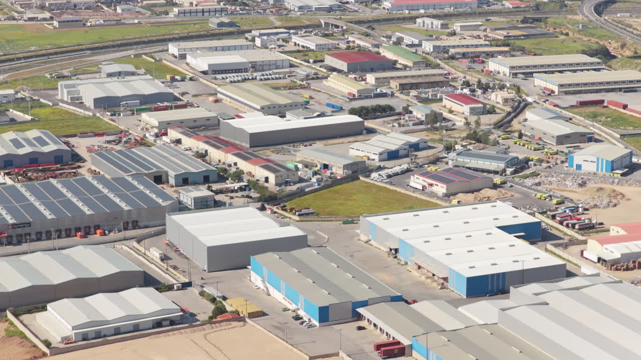 Vasto parque industrial con numerosos almacenes, fábricas y centros logísticos visto desde arriba, mostrando la escala del comercio moderno, la fabricación y las operaciones de la cadena de suministro global