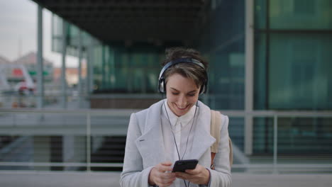 Retrato-De-Una-Joven-Y-Feliz-Mujer-De-Negocios-Ejecutiva-Enviando-Mensajes-De-Texto-Navegando-Usando-Una-Aplicación-De-Redes-Sociales-Para-Teléfonos-Inteligentes-Disfrutando-De-La-Música-Usando-Audífonos