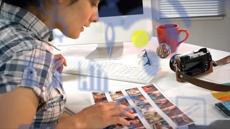 animation of digital icons over caucasian female photographer looking at the photographs at office