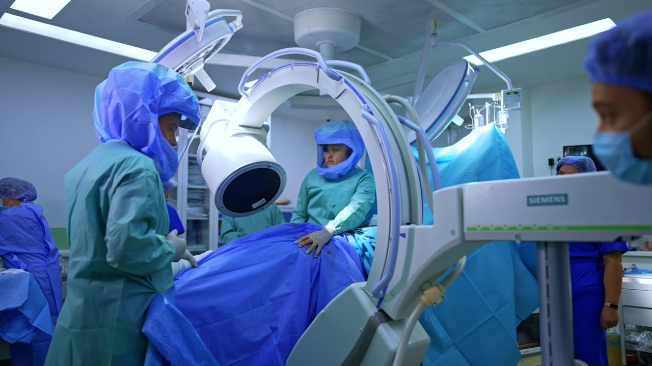 I medici posizionano il tavolo operatorio con il paziente sotto la macchina radiografica a C-arm. Preparazione per un intervento di traumatologia