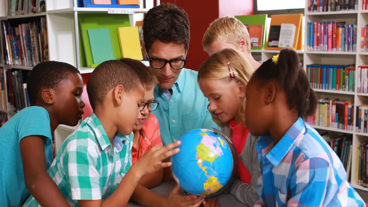 los niños y el maestro mirando el globo en la biblioteca