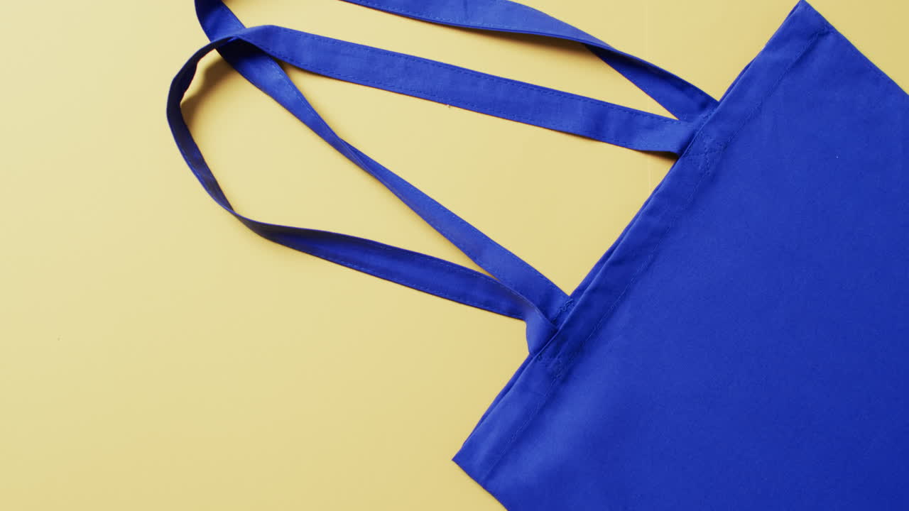 video de una bolsa de lienzo azul con espacio de copia en fondo amarillo