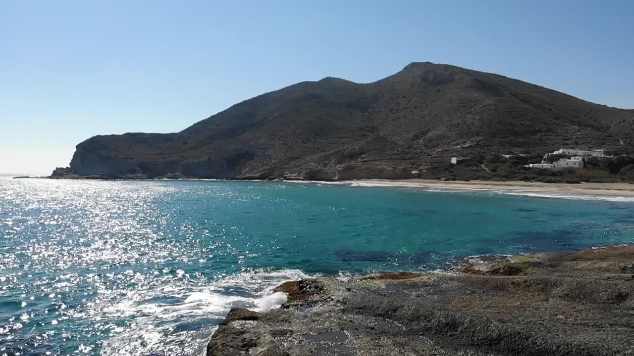 파도가 바위에 부히면서 푸른 물 위의 산으로 향하는 공중 도리