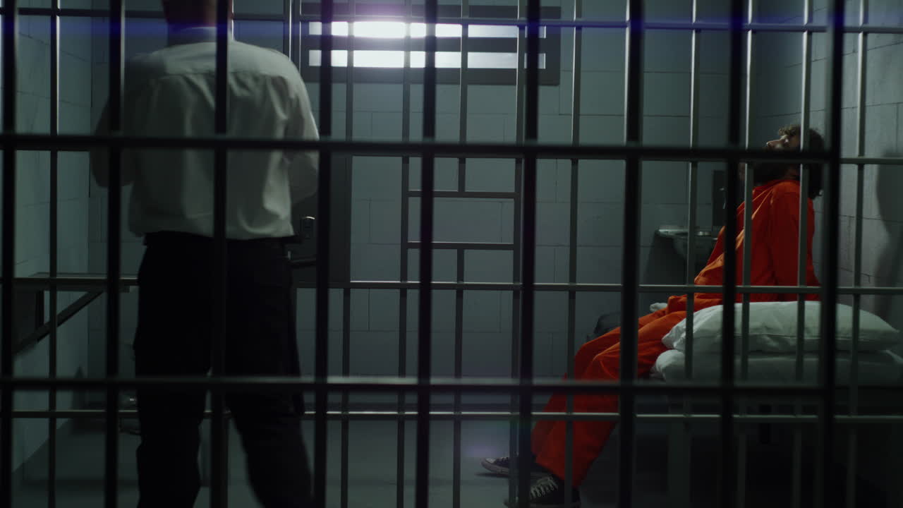 el trabajador de la prisión abre la celda del prisionero y sale.