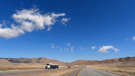 driving along a southern california highway through the mojave desert with wind turbines on the distant mountains - driver point of view