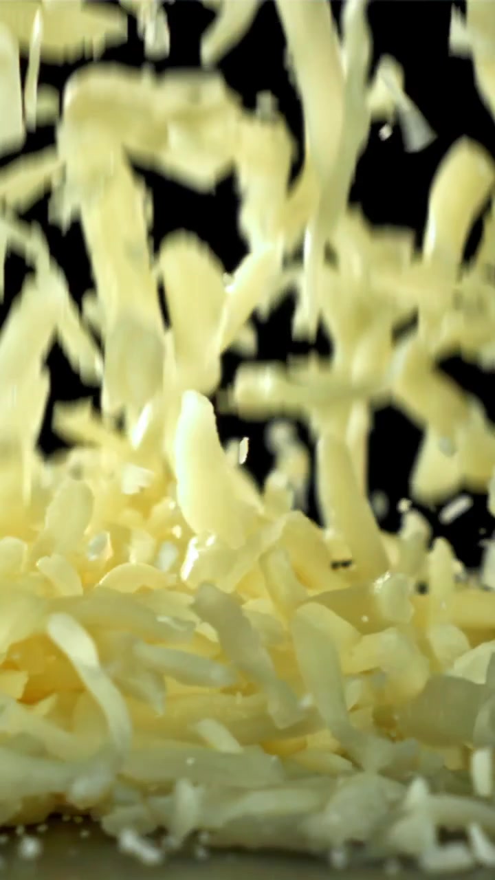 Grated Cheese Falling in Slow Motion on a Black Background