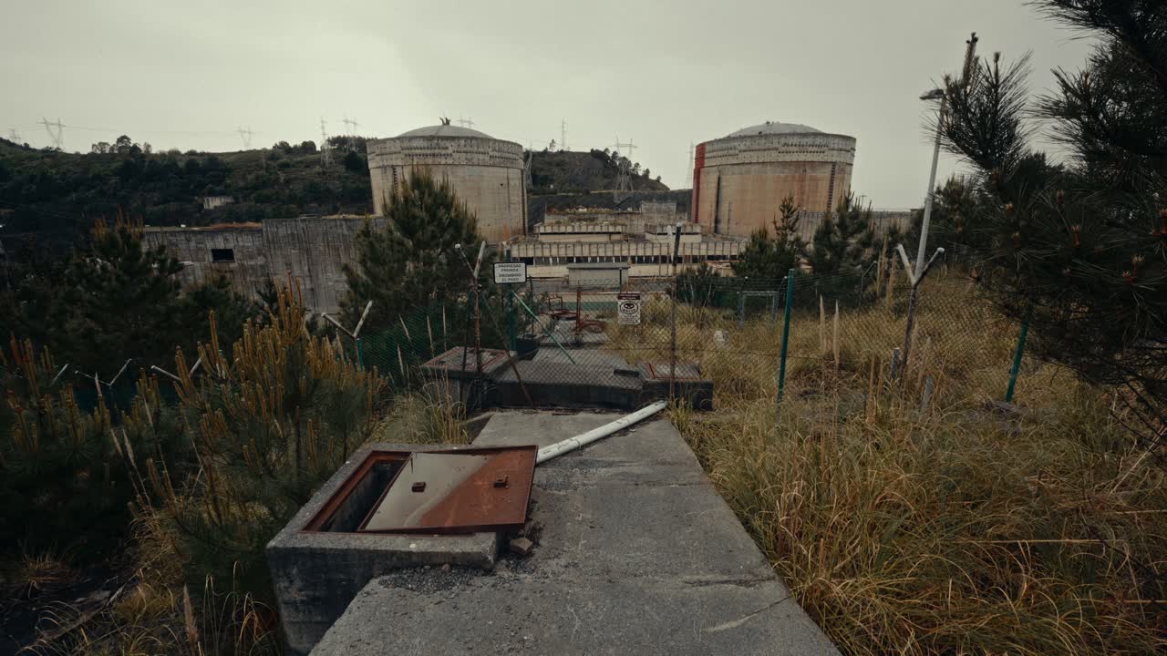 Abandoned Nuclear Power Plant with Overgrown Fences and Cooling Towers