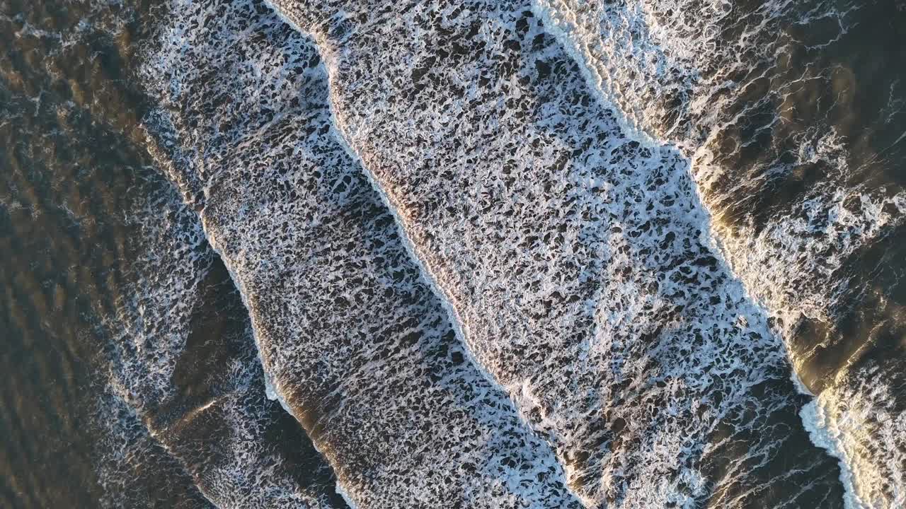 Fugleperspektiv drone-luftfoto av Nordsjøens havbølger som slår inn mot strandbredden tidlig morgen ved soloppgang, Seaburn Beach, Sunderland, England, Storbritannia