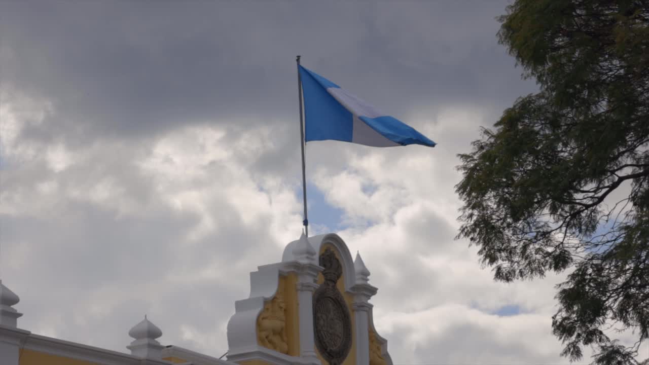 Guatemala national flag blue white stripes top of building waving Central America