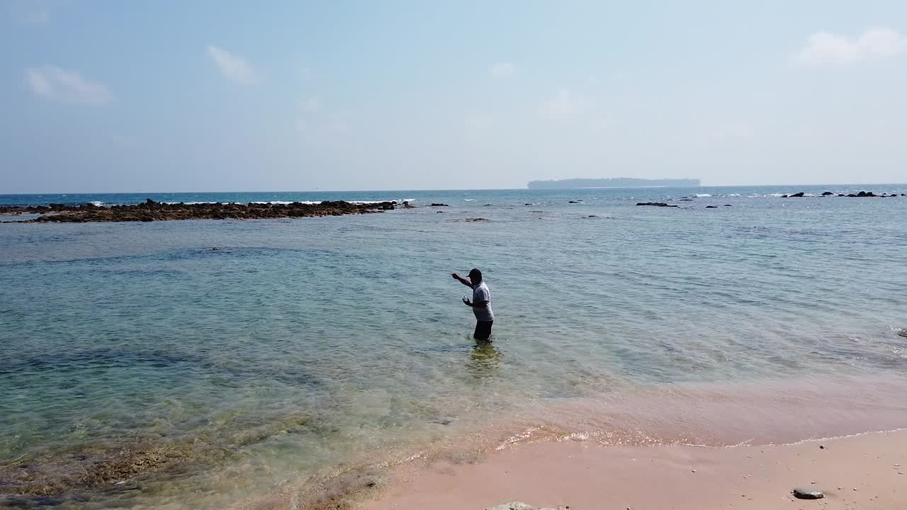 한 어부가 오늘의 마지막 던지기를 하고 안다만 해수에 허리 깊이 서서 줄을 감고 낚싯바늘을 감습니다.