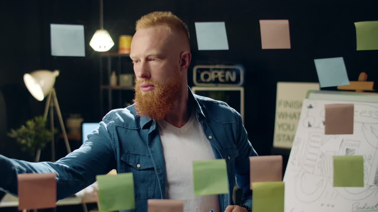 близкий вдумчивый бизнесмен ищет наклейки на стеклянной доске в коворкинге.