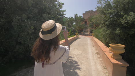 woman taking a picture of a beautiful castle in a garden