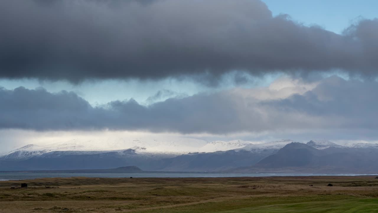 tiro de lapso de tiempo de nubes voladoras en el cielo sobre el paisaje de islandia y montañas nevadas en segundo plano