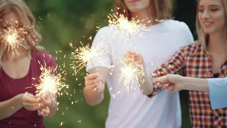 happy friends with sparklers having fun outdoors