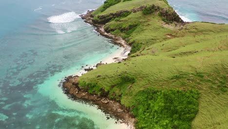 boat anchored in cove at bukit merese lombok with tropical turquoise waves crashing