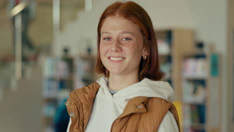 portrait of a smiling redhead woman in a library