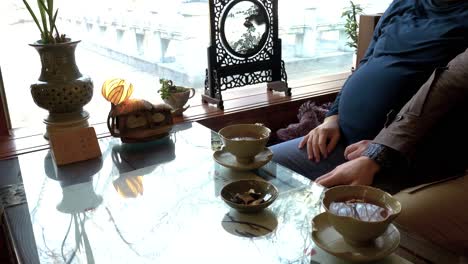 man affectionately puts hand on pregnant wife's leg in traditional korean tea shop