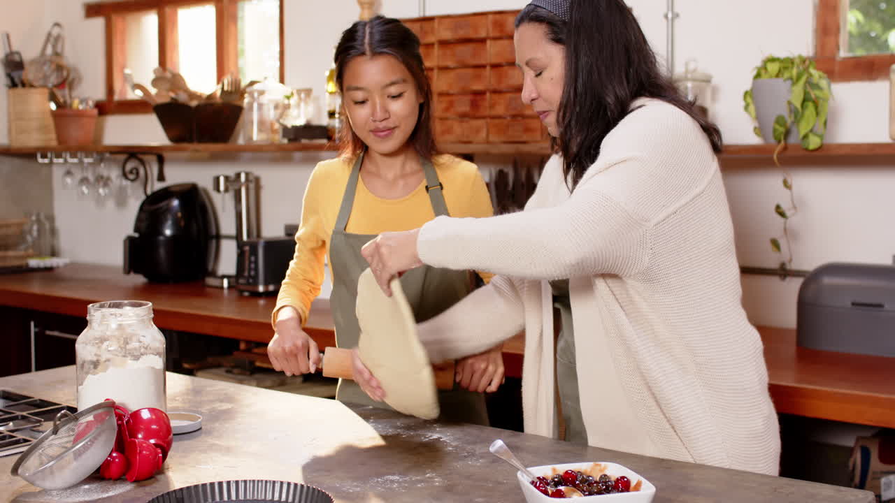multiracial grandmother and young woman rolling dough together in cozy kitchen, at home