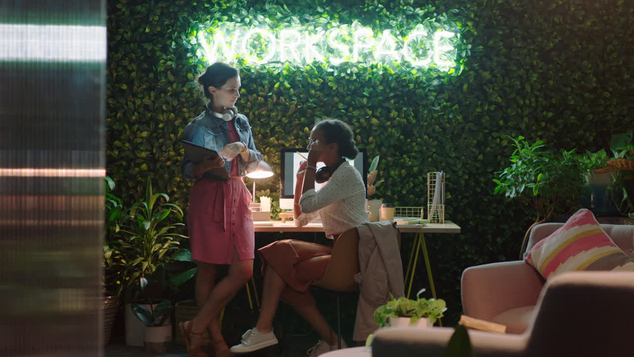 태블릿 컴퓨터를 사용하여 늦게 일하는 사업가 팀 리더 여성 아이디어를 공유하는 동료가 화면을 가리키는 것을 보여주는 밤에 현대적인 사무실에서 프로젝트 정보를 논의하는 것