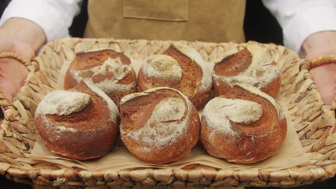 The baker holds in hands a of fresh bread close-up. Artisan bread is making by skill bakers using natural and high-quality ingredients. Food with health and flavour benefits.