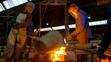 group of workers pouring molten metal in mold at workshop 4k