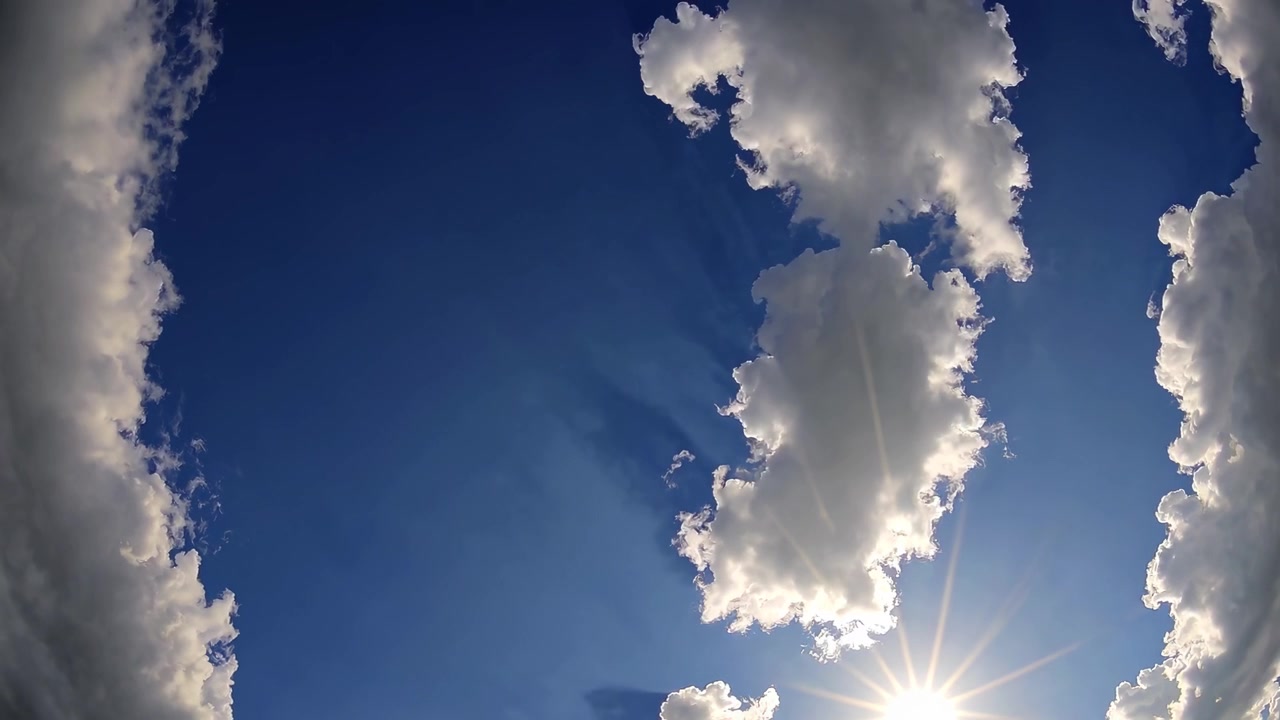 Il sole splendente splende attraverso le nuvole bianche nel cielo blu