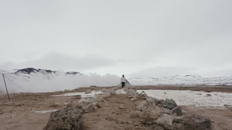man walk closer through rock formation at myvatn geothermal area, iceland